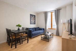 Un salon moderne avec une table à manger, un canapé et un téléviseur.