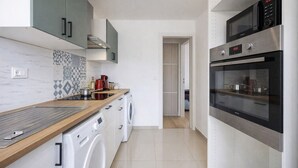 A modern kitchen with a wooden countertop, built-in appliances, and a washing machine. - Charming 2-Bedroom Apartment in Downtown - Cozy Houses (Reims)