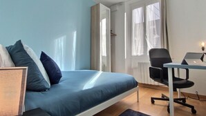A bedroom with a bed, a desk, a chair, and a window. - Charming 2-Bedroom Apartment in Downtown - Cozy Houses (Reims)