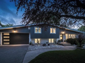 A modern two-story house with a garage, a well-lit entrance, and a landscaped front yard.
