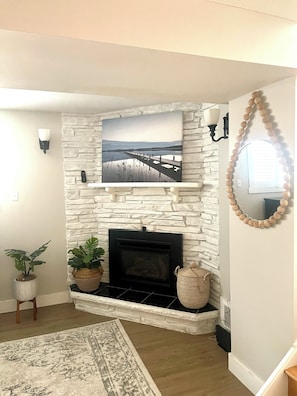 A living room with a stone fireplace, a mounted picture, and a decorative mirror.