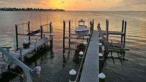 Un muelle con un bote, pasarelas de madera y un atardecer sobre el agua.