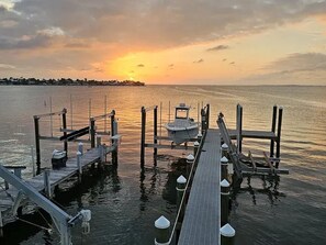 A dock with a boat, wooden walkways, and a sunset over the water. - Lovely 2-bedroom house with AC in enjoyable Key Largo (Key Largo)
