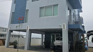 Un edificio moderno de dos pisos con balcón, garaje y un pequeño espacio exterior con un bote.