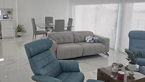 Una sala de estar moderna con un sofá, sillas, una mesa de centro y un comedor.
