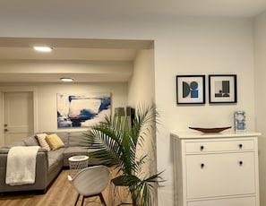 A living room with a grey sofa, a white cabinet, and a large abstract painting on the wall.