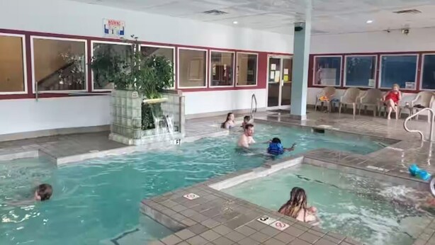An indoor swimming pool with multiple lanes, a water slide, and a seating area with chairs. - Tiny Home-Cabin near Helen Ga.Lake/Beach/Pools/Playgrounds/Diner/Putt Putt/Sauna (Cleveland)