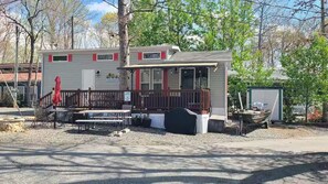 A mobile home with a porch, outdoor seating, and a boat in the background. - Tiny Home-Cabin near Helen Ga.Lake/Beach/Pools/Playgrounds/Diner/Putt Putt/Sauna (Cleveland)