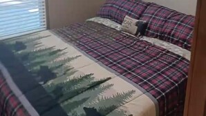 A bedroom with a bed, a window with blinds, a painting on the wall, and a door. - Tiny Home-Cabin near Helen Ga.Lake/Beach/Pools/Playgrounds/Diner/Putt Putt/Sauna (Cleveland)