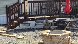 A deck with outdoor furniture and a fire pit in front of a building with a 'WELCOME' sign. - Tiny Home-Cabin near Helen Ga.Lake/Beach/Pools/Playgrounds/Diner/Putt Putt/Sauna (Cleveland)