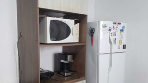 Una cocina equipada con microondas, cafetera y refrigerador.