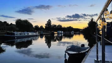 A calm river with boats docked, a dock, and a clear sky.