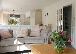 A cozy living room with a grey sofa, a wooden coffee table, and a vase with flowers. - Island Cottage Rod Eyot (Henley-on-Thames)