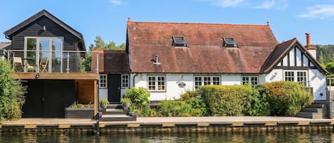 A traditional building with a white facade, a red-tiled roof, and a dock extending into a body of water.