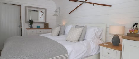 A bedroom with a bed, nightstand, dresser, and a wooden paddle on the wall.