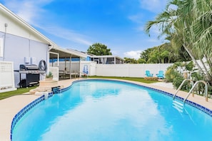 Ein Garten mit Swimmingpool, Grill und überdachter Terrasse.