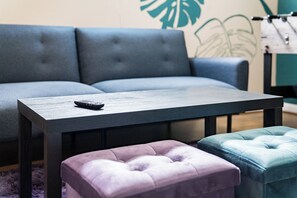 Ein modernes Wohnzimmer mit einer Couch, einem kleinen Tisch und zwei Hocker.