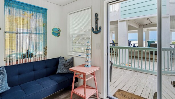 Una habitación con un sofá azul, una mesita y vistas a la playa a través de un ventanal.