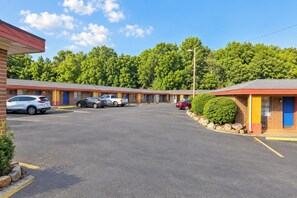A motel with multiple rooms, a parking lot, and a forested backdrop.
