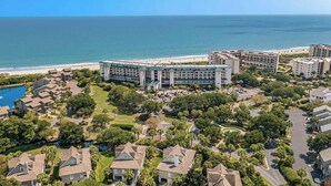 Un hôtel situé sur la côte, composé de plusieurs bâtiments, doté d’une piscine et offrant une vue sur la plage.