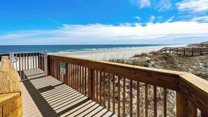Une terrasse en bois offrant une vue sur la plage et l’océan.