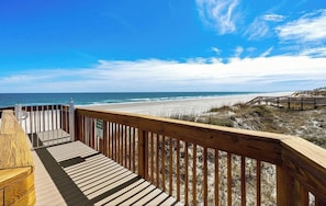 Eine Holzterrasse mit Blick auf den Strand und den Ozean.