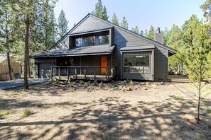 A modern two-story house with a large deck, surrounded by trees. - 20 Camas - Sunriver Charm, Hot Tub, Fireplace, AC, 10 SHARC Passes (Sunriver)
