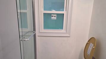 Un baño con cabina de ducha de vidrio, inodoro y lavamanos con encimera de granito.