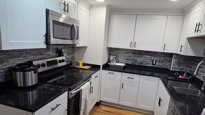 A modern kitchen with white cabinets, a black countertop, a microwave, a stove, and a dishwasher. - Alimot Spa House:Private INDOOR Hot Tub  Near SU & Downtown  Named for My Mother (Syracuse)