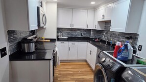A compact kitchen with white cabinets, a built-in oven, a washing machine, and a sink. - Alimot Spa House:Private INDOOR Hot Tub  Near SU & Downtown  Named for My Mother (Syracuse)