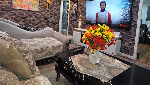 A living room with a sofa, a coffee table, a TV, and a floral centerpiece. - Alimot Spa House:Private INDOOR Hot Tub  Near SU & Downtown  Named for My Mother (Syracuse)