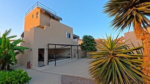 A modern two-story building with a flat roof, a covered outdoor seating area, and a paved courtyard. - Private Home—Ocean View with Pool and Fire Pit (Perfect for Vacations) (BCS)