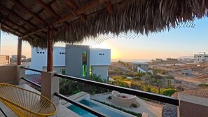 A balcony with a thatched roof, a pool, and a view of buildings and landscape. - Private Home—Ocean View with Pool and Fire Pit (Perfect for Vacations) (BCS)