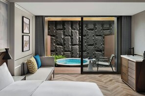 A modern hotel room with a large bed, a sofa, a dining table, a small kitchen area, and a view of a swimming pool through a glass door. - Le Méridien Yichang Sanxia (Yichang)