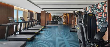 Une salle de sport équipée de tapis de course, d’appareils de musculation et dotée d’un sol à motifs.