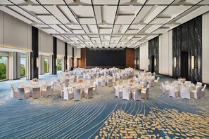 A large conference room with round tables, white chairs, and a stage at the front. - Le Méridien Yichang Sanxia (Yichang)