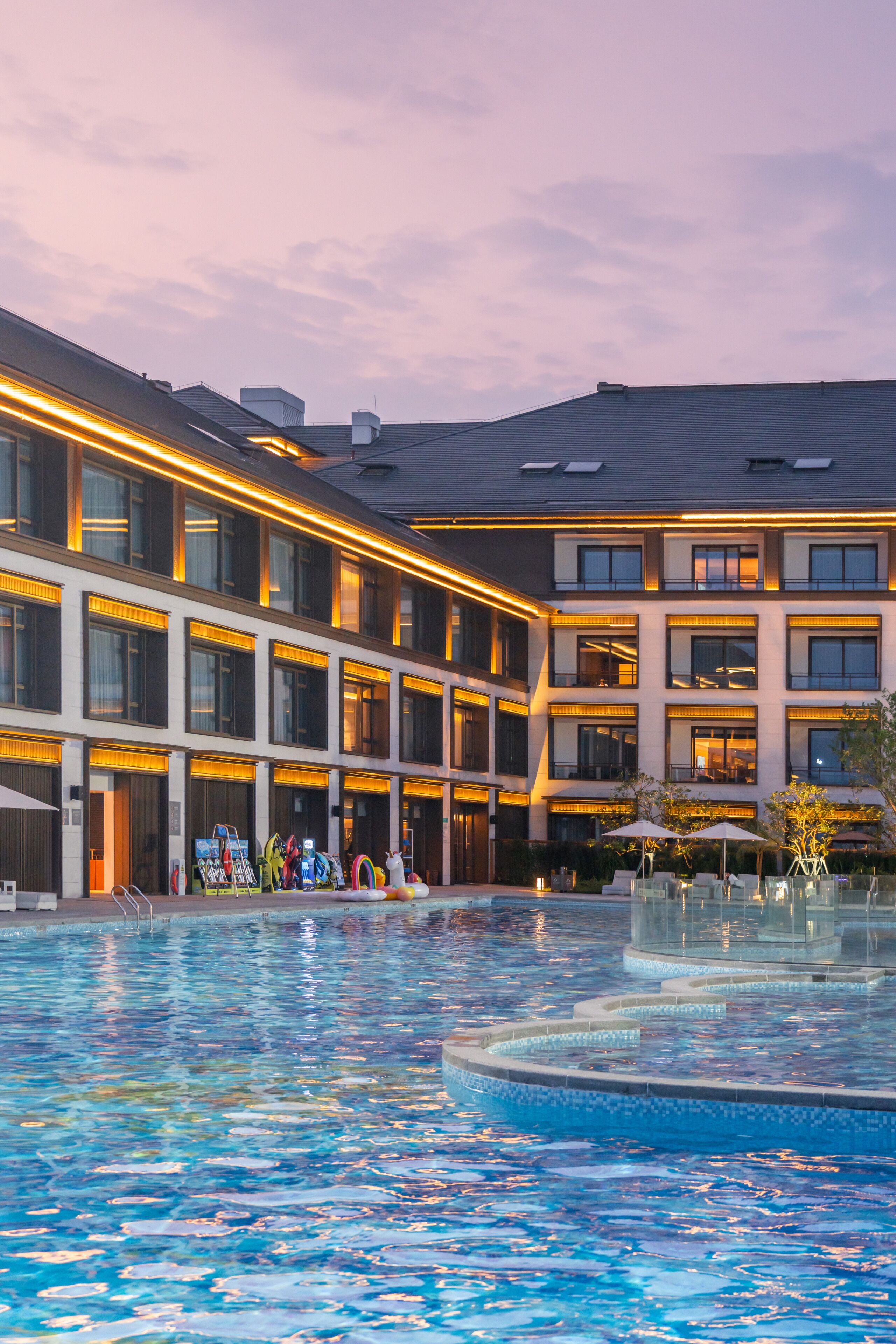 Un hotel con piscina, varios balcones y un diseño arquitectónico moderno.