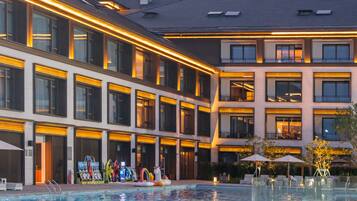 Un hotel con piscina, varios balcones y un diseño arquitectónico moderno.