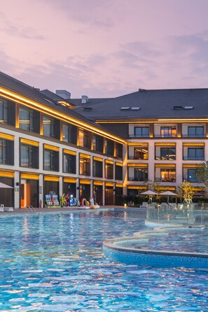 A hotel with a swimming pool, multiple balconies, and a modern architectural design.