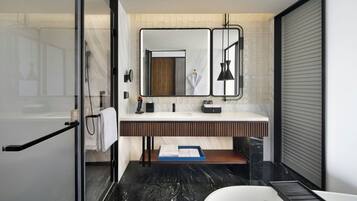 A modern bathroom with a glass shower enclosure, a white bathtub, a vanity with a mirror, and a towel rack.