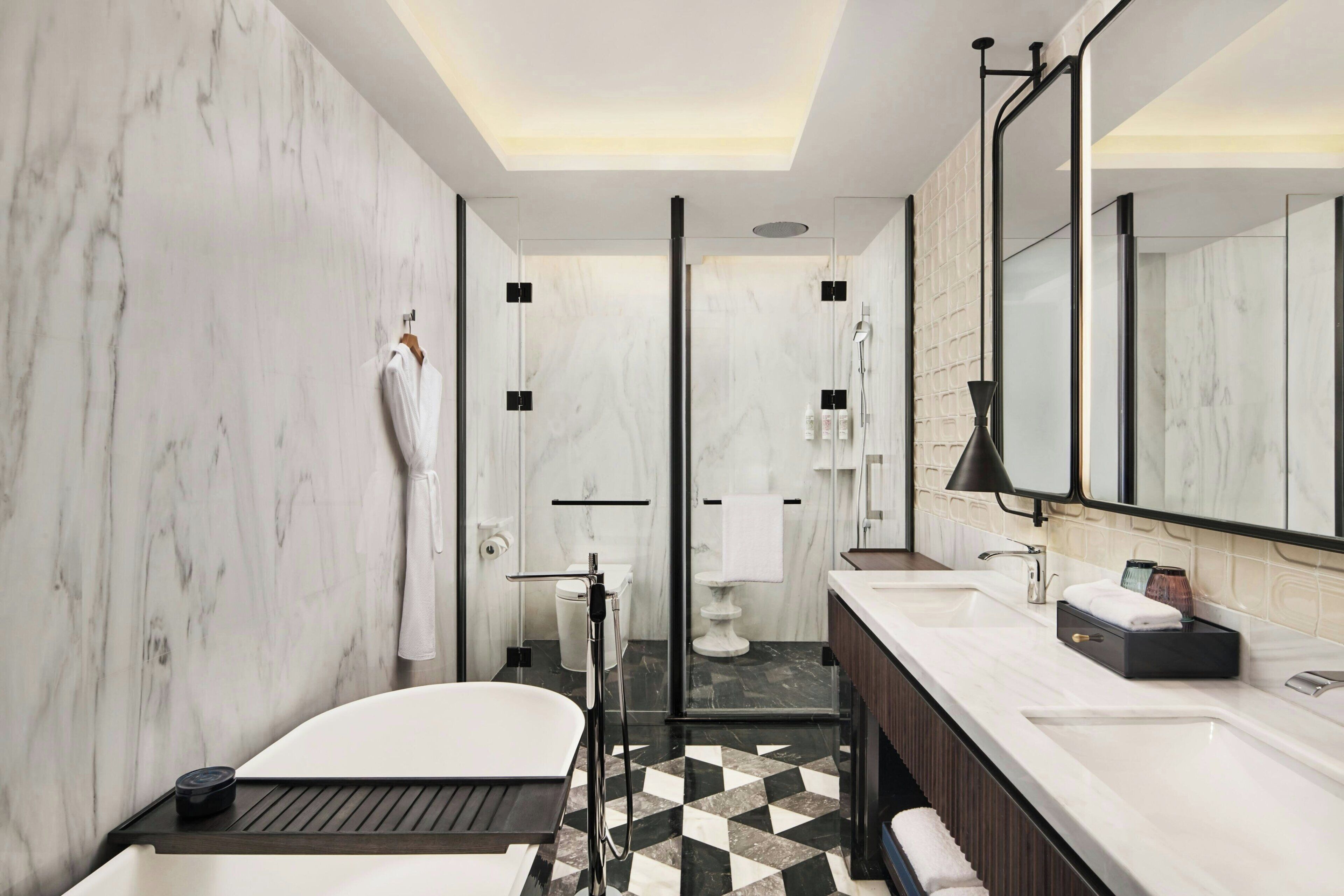 A modern bathroom with a bathtub, a large mirror, a vanity with a sink, and a shower area.