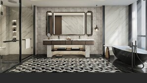 Un baño moderno con tocador de mármol, un espejo grande, una bañera independiente y un piso con estampado geométrico.
