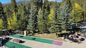 A patio area with outdoor seating, a fire pit, and a green space for activities. - Grand Timber Lodge 3BR Resort Condo (Breckenridge)