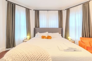 A neatly made bed with pillows, a bedside lamp, and a chair.