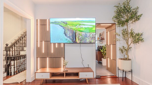 A modern living room with a flat-screen TV, wooden entertainment unit, and a staircase. - NEW-Spacious 3BR-Office-Game Room-Laundry In Unit (Everett)