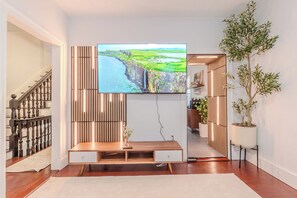 A modern living room with a flat-screen TV, wooden entertainment unit, and a staircase. - NEW-Spacious 3BR-Office-Game Room-Laundry In Unit (Everett)