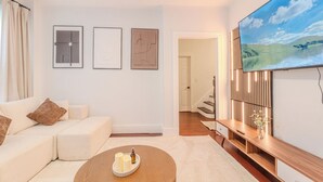 A modern living room with a sofa, a coffee table with candles, a TV, and framed artwork on the wall. - NEW-Spacious 3BR-Office-Game Room-Laundry In Unit (Everett)