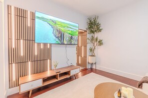 A modern living room with a flat-screen TV, wooden panel wall, a plant, and a sofa. - NEW-Spacious 3BR-Office-Game Room-Laundry In Unit (Everett)