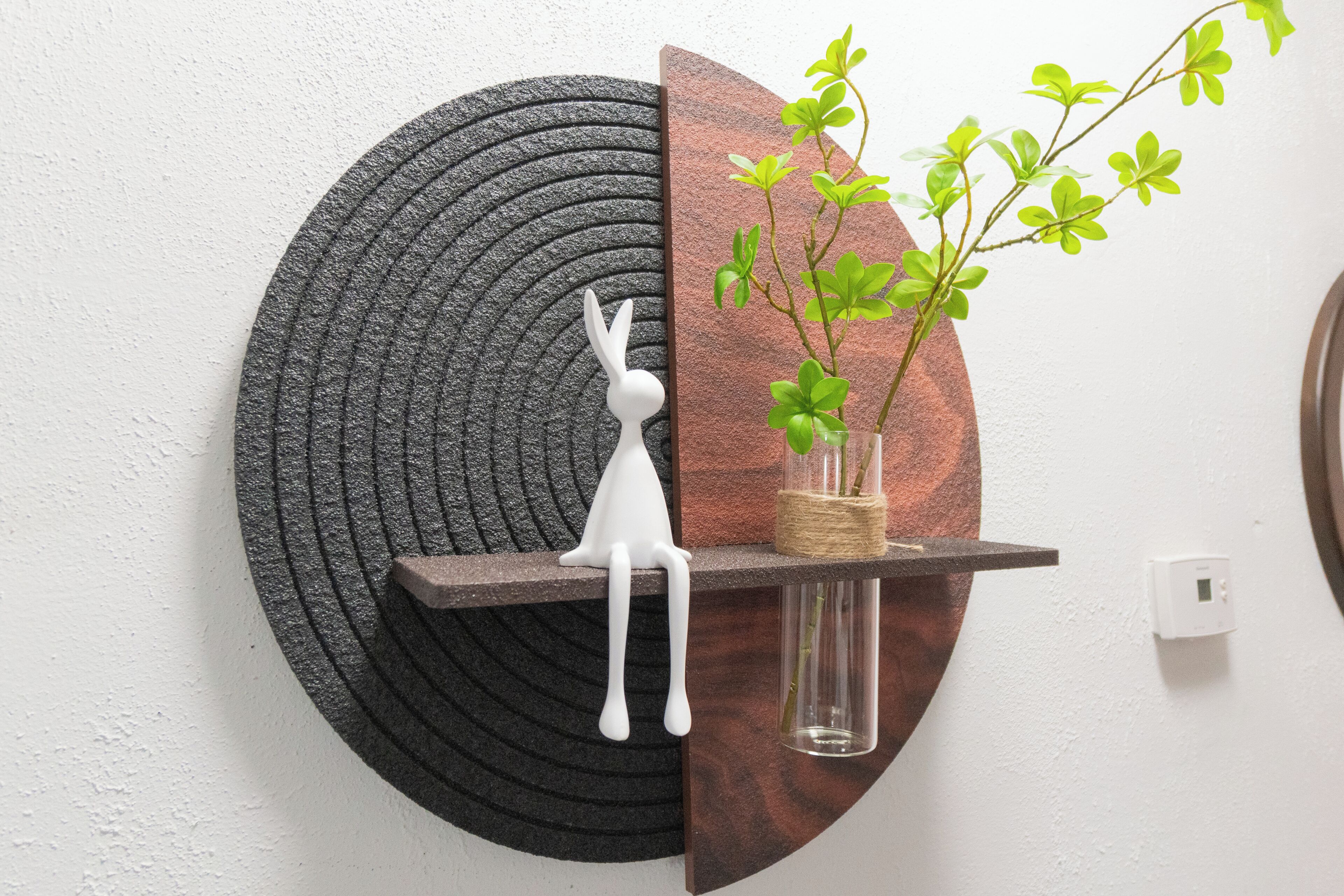 A wall-mounted shelf with a white rabbit figurine and a potted plant.