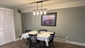 Un coin repas comprenant une table, des chaises, un lustre et un tableau encadré accroché au mur.